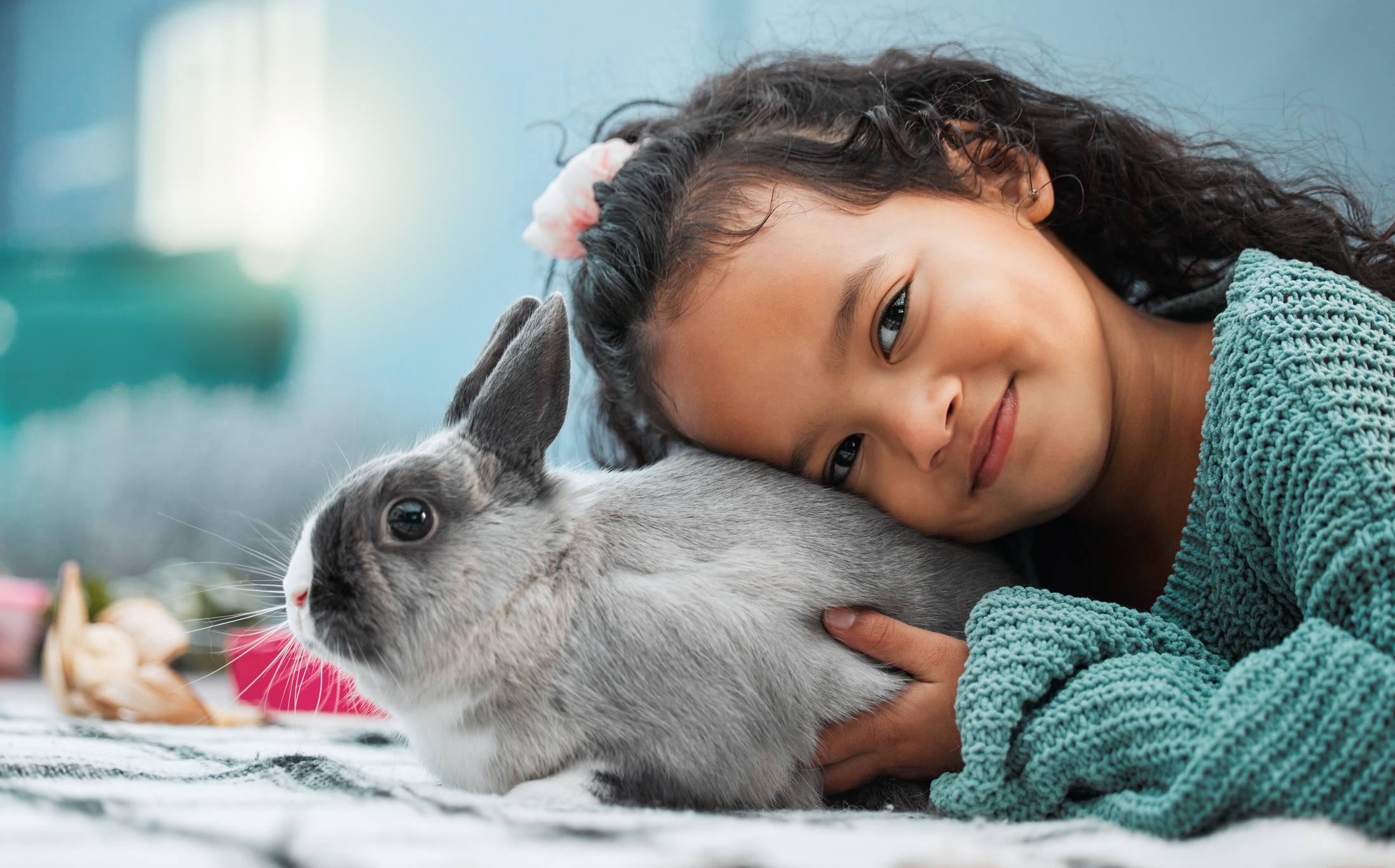 Smiling girl holding pet rabbit at home